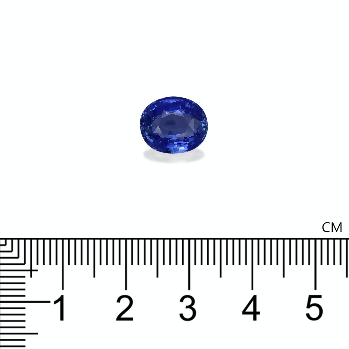 Le Saphir Bleu · 4,99ct de Bonnot Paris, une petite pierre précieuse bleue de taille ovale, repose sur une surface blanche à côté d'une échelle centimétrique, indiquant sa taille comme étant légèrement supérieure à 1 cm.