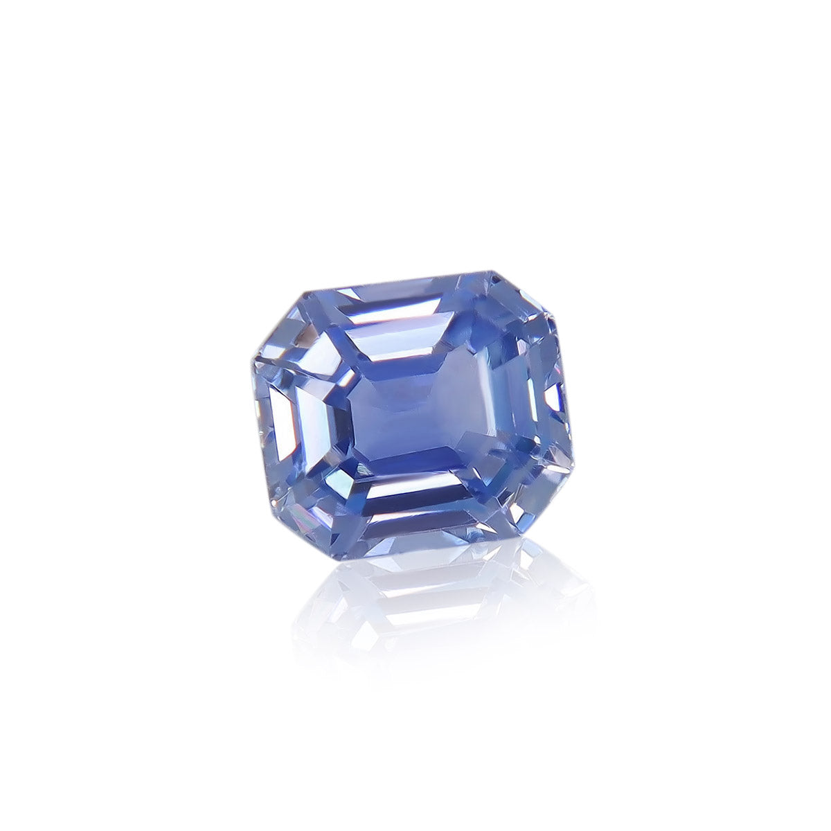 Le Saphir Bleu 1,63 ct de Bonnot Paris est une pierre précieuse bleue taille émeraude, reflétant magnifiquement la lumière sur sa surface sur un fond blanc uni, mettant en valeur sa teinte bleue vibrante et ses bords précis.
