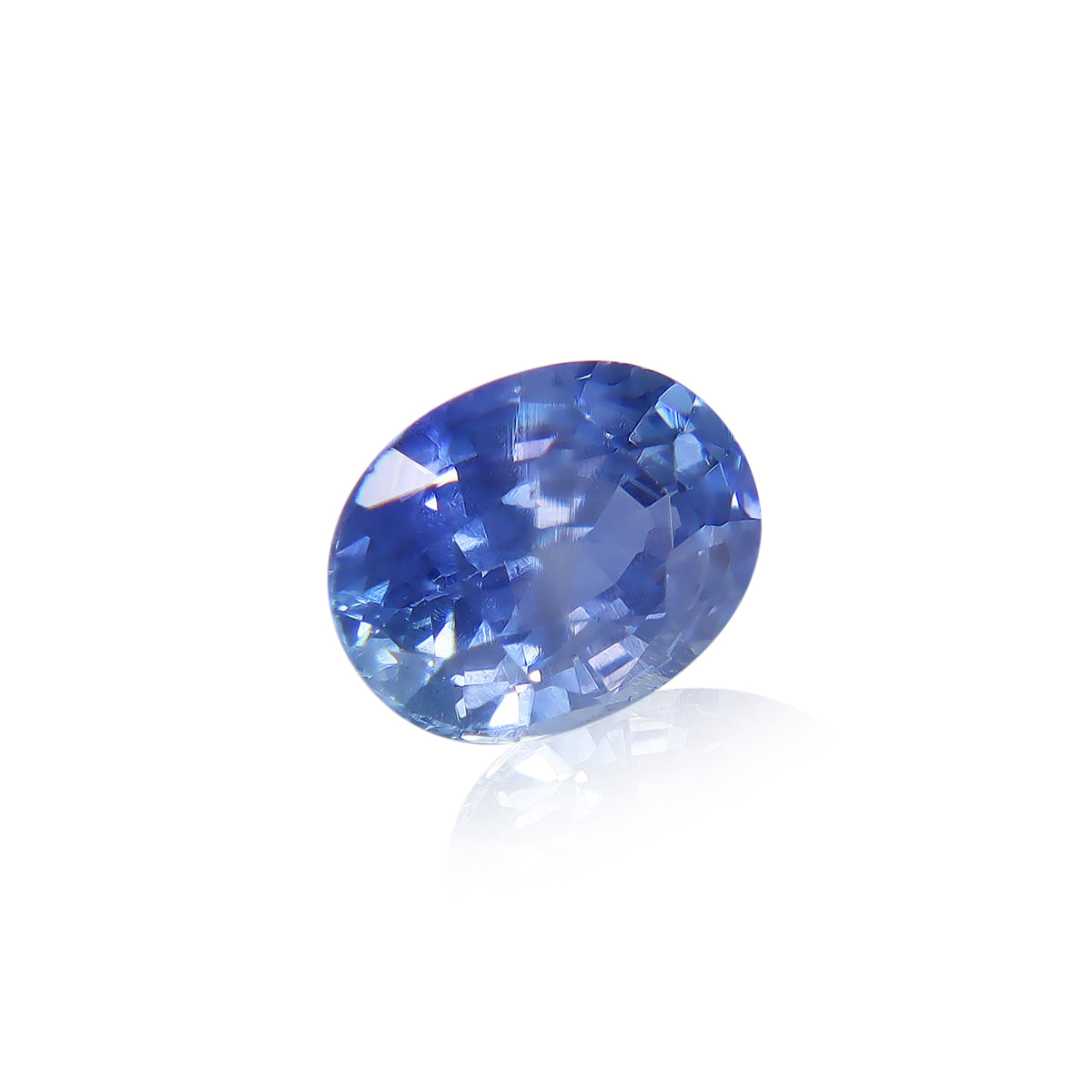 Le Saphir Bleu · 1,28 ct de Bonnot Paris est une pierre précieuse bleue de forme ovale aux facettes complexes, présentant un jeu de lumière vibrant et diverses nuances de bleu sur un fond blanc doux pour une apparence étincelante et réfléchissante.