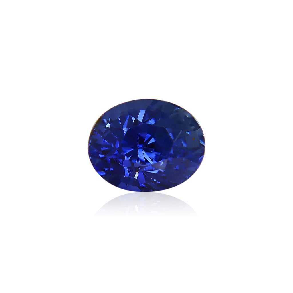 Le Saphir Bleu · 2,12 ct de Bonnot Paris est une superbe pierre précieuse bleue de taille ovale avec une surface facettée qui reflète la lumière, affichant des nuances de bleu profond sur un fond blanc uni.
