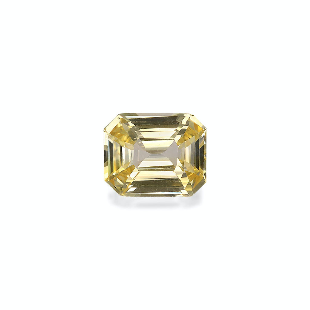 Le Saphir Jaune de Bonnot Paris, une pierre précieuse jaune taille émeraude de 3,06 carats, présente des facettes en escalier et est présenté sur un fond blanc uni lorsqu'il est vu d'en haut.