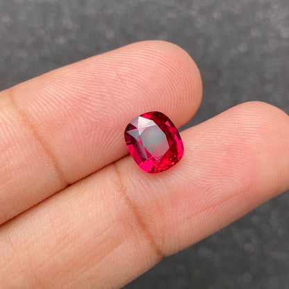 Une main tient une pierre précieuse Rubis du Mozambique · 2,57 ct de Bonnot Paris sur un fond gris texturé, mettant en valeur sa teinte rose foncé et ses facettes exquises.