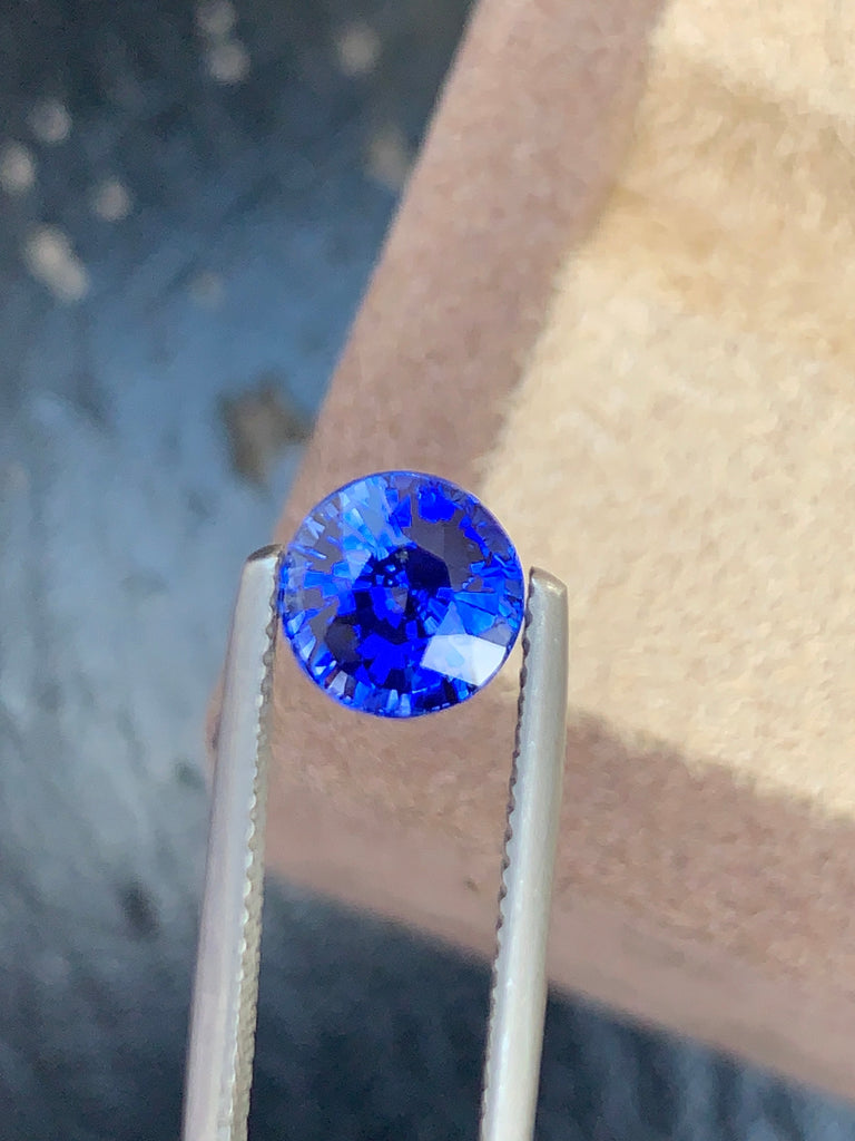 Un Saphir Bleu brillant de 2,53 ct, rond et brillant, de Bonnot Paris, est maintenu par une pince en argent, mettant en valeur sa taille facettée éclatante et ses teintes bleu profond. Le fond délicatement flouté rehausse la clarté et la beauté unique de la gemme, l'une des plus belles pierres précieuses.