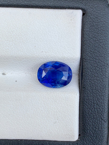 Un Saphir bleu vibrant de 3,59 ct de Bonnot Paris est présenté sur une surface blanche texturée avec une bordure noire, mettant en valeur sa teinte bleu profond et sa clarté grâce à sa taille facettée.
