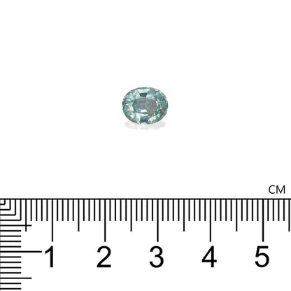 Une Alexandrite ovale bleu clair de 2,31 ct, hautement facettée, de Bonnot Paris est présentée au-dessus d'une règle, mesurant environ 0,8 cm de longueur sur un fond blanc uni car elle reflète la lumière avec brio.