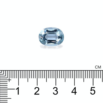 Une superbe Bonnot Paris Aigue-Marine · 5,35 ct, taillée dans une coupe ovale classique, repose sur une surface blanche au-dessus d'une règle noire marquée en centimètres, mettant en valeur sa largeur impressionnante d'environ un centimètre.