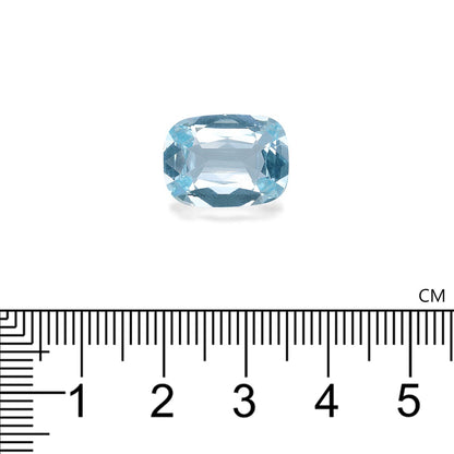 Une pierre précieuse Aigue-Marine bleu clair, taille coussin, de Bonnot Paris, repose sur un fond blanc au-dessus d'une règle métrique, indiquant une largeur d'environ 1,3 cm. Son allure moelleuse renforce son charme.