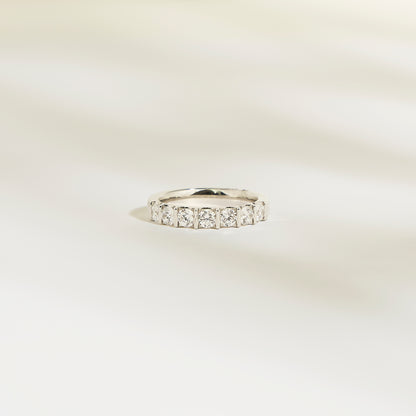 L'Alliance La Subtile de Bonnot Paris est une bague en argent sertie de pierres taille carrée, semblables à des diamants. Son éclat brillant évoque un luxe discret, issu d'une collection exquise. Elle repose sur une surface lisse et légère, avec des ombres douces et floues en arrière-plan.