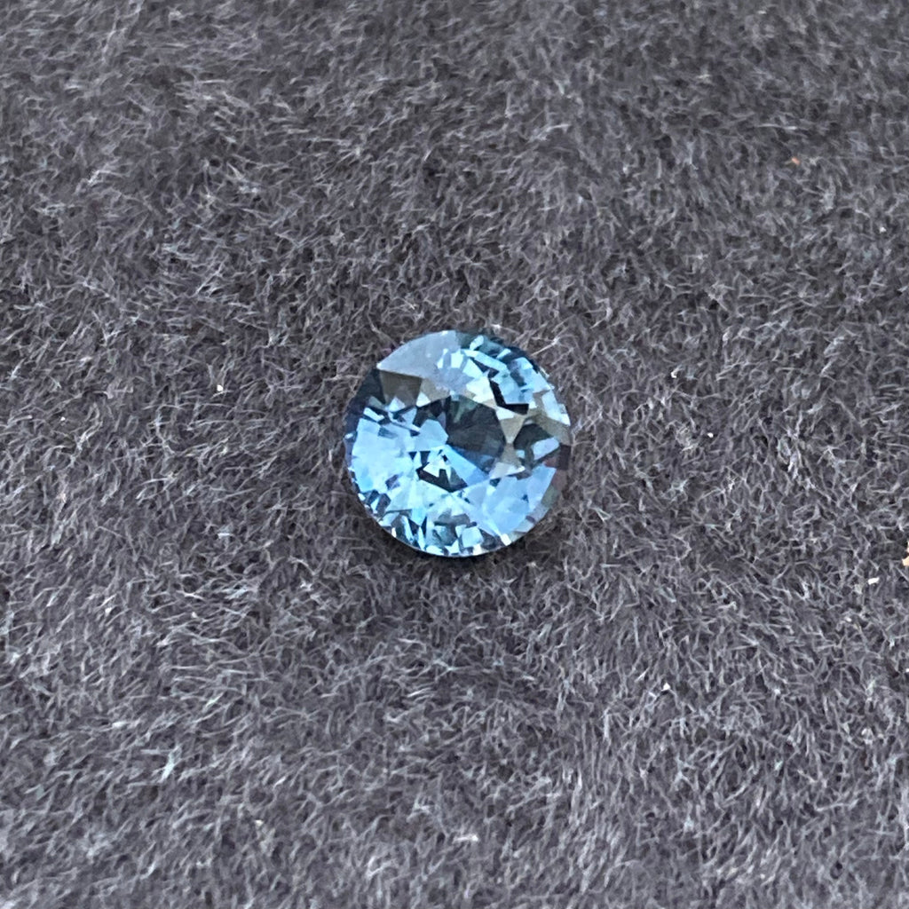 Le Saphir Teal, une pierre précieuse de 1,55 carat de Bonnot Paris, repose élégamment sur un fond texturé sombre, mettant en valeur sa beauté raffinée.