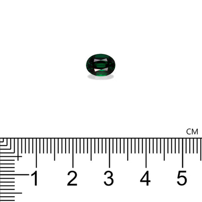 La Tourmaline Chrome Bonnot Paris, une petite pierre vert foncé de taille ovale pesant 1,63 ct, est sertie sur un fond blanc. En dessous, une règle graduée en cm et en mm indique sa longueur, légèrement supérieure à 1 cm.