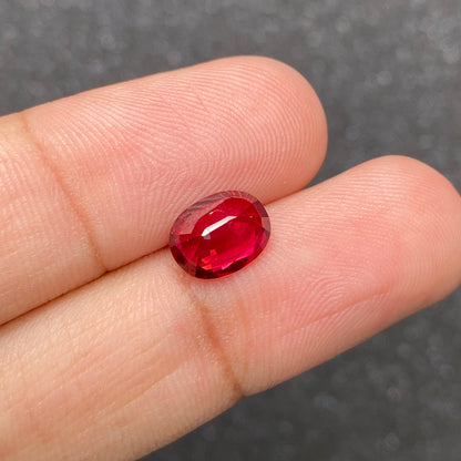 Le Rubis du Mozambique, une pierre ovale de 2,59 carats de Bonnot Paris, se détache sur un fond gris flou.