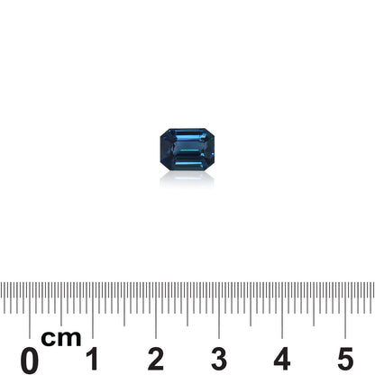Une petite pierre précieuse Saphir Teal taille émeraude de 2,57 carats de Madagascar par Bonnot Paris est placée sur une surface blanche au-dessus d'une échelle centimétrique allant de 0 à 5, indiquant sa taille.
