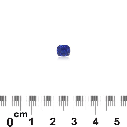 Le Saphir Bleu · 1,2 ct, une pierre précieuse bleu profond de Bonnot Paris, est centré sur un fond blanc au-dessus d'une règle mesurant sa taille coussin à environ 1 centimètre.