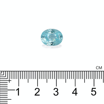 Une tourmaline paraïba bleu clair de forme ovale, provenant de Bonnot Paris, pesant 6,48 carats, est posée sur un fond blanc. Une règle graduée en centimètres, située en dessous, indique sa petite longueur d'environ 1 cm.