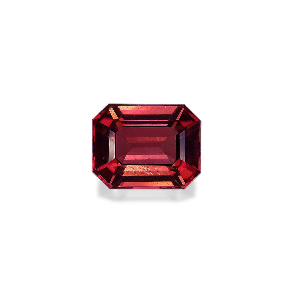 Une Tourmaline Rose taille émeraude de 6,25 carats de Bonnot Paris, aux teintes rouges vibrantes et aux multiples facettes reflétant la lumière pour des nuances et une brillance variées, sur un fond blanc uni.