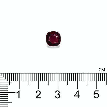 Un Rubis du Mozambique taille coussin, 3,02 ct de Bonnot Paris, est placé au-dessus d'une règle métrique sur fond blanc, montrant sa largeur légèrement supérieure à 1 cm.