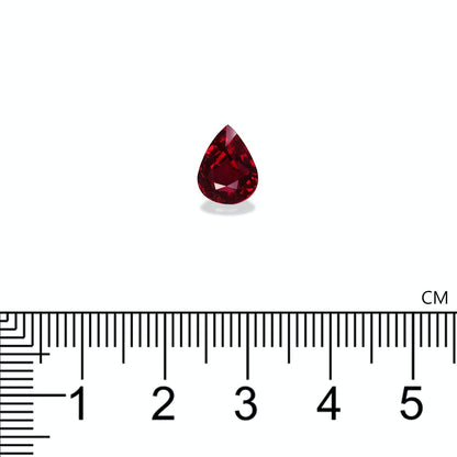 Une pierre précieuse Rubis du Mozambique rouge en forme de poire de Bonnot Paris, mesurant environ 1,5 cm de hauteur, est représentée sur un fond blanc au-dessus d'une règle avec des repères en centimètres.
