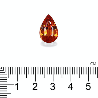 Le Grenat Spessartite · 7,46 ct de Bonnot Paris, une pierre précieuse en forme de poire dans différentes nuances d'orange avec des coupes complexes, est présenté au-dessus d'une règle centimétrique pour comparaison d'échelle.