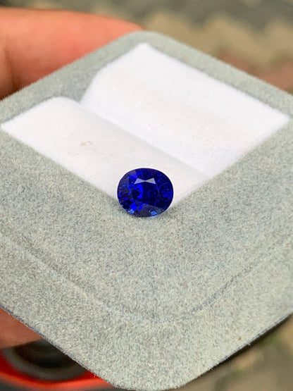 Le Saphir Bleu de 2,51 carats de Bonnot Paris [NOUVEAU] est présenté dans un écrin gris ouvert sur un coussin blanc. Sa teinte bleu profond reflète brillamment la lumière. L'attrait de cette pierre précieuse est magnifiquement mis en valeur sur un fond légèrement flou.