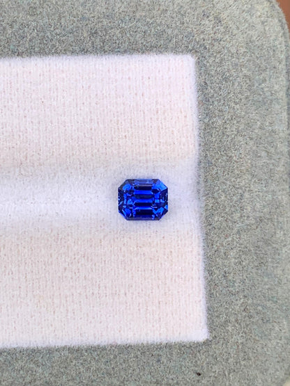 Le Saphir bleu • 1,02ct de [NOUVEAU] Bonnot Paris est une gemme taille émeraude du Sri Lanka, reposant sur un doux tissu blanc et gris, mettant en valeur ses facettes claires et sa riche couleur bleue.