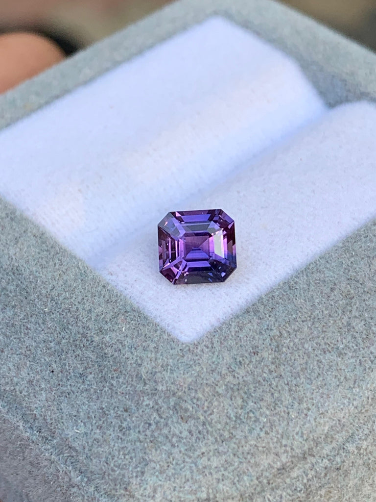 Un saphir violet octogonal éclatant de 1,20 carat, provenant du Sri Lanka, signé Bonnot Paris, est élégamment présenté dans un écrin en velours gris. Cette pierre précieuse rare reflète magnifiquement la lumière, mettant en valeur sa clarté et sa couleur vibrante sur un fond délicatement flou.
