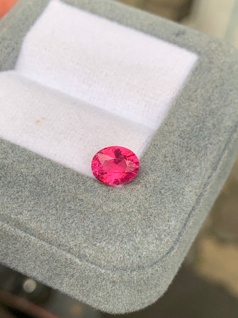 La pierre précieuse Spinelle Mahenge • 1,55ct de Bonnot Paris, dans une teinte rose ronde et vibrante, est élégamment présentée sur un coussin blanc dans un écrin à bijoux gris.