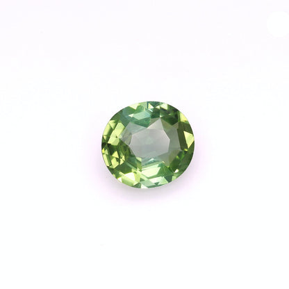 La Tourmaline Verte de Bonnot Paris · 6,17 ct est une pierre précieuse verte ronde et facettée, présentée sur un fond blanc uni et révélant diverses nuances de vert lorsqu'elle capte la lumière.