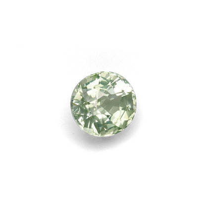 Une Tourmaline Verte Bonnot Paris · 7,79 ct, ronde et facettée, scintille d'une teinte verte translucide sur un fond blanc uni, ses facettes créant un effet de lumière chatoyant.
