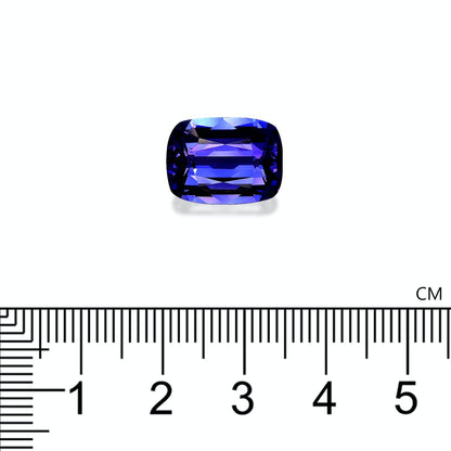 Une petite tanzanite rectangulaire de 7,25 carats, taillée en facettes par Bonnot Paris, est placée sur un fond blanc. En dessous, une règle graduée en centimètres indique une taille légèrement supérieure à 1 cm.
