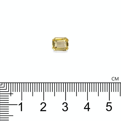 Le Saphir Jaune · 2,05ct de Bonnot Paris, une petite pierre précieuse jaune taille émeraude, est placé sur une surface blanche près d'une règle centimétrique, indiquant que la taille de la pierre est d'environ 0,8 cm.