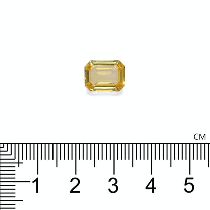 Une pierre précieuse jaune rectangulaire de Bonnot Paris, rappelant un saphir rectangulaire non chauffé, est placée au-dessus d'une règle et mesure un peu plus d'1 cm de large. Ce Saphir Jaune de 4,04 carats présente une exquise taille émeraude aux bords biseautés.