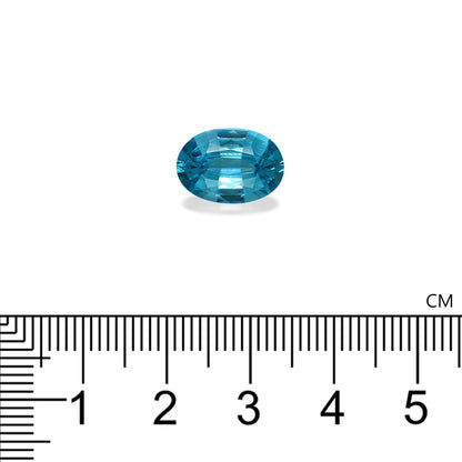 Une pierre précieuse Zircon Bleu de 5,79 ct de Bonnot Paris présentée est une pierre précieuse de taille ovale sur fond blanc avec sa couleur turquoise vibrante assortie à un gros plan d'une règle en centimètres pour l'échelle.