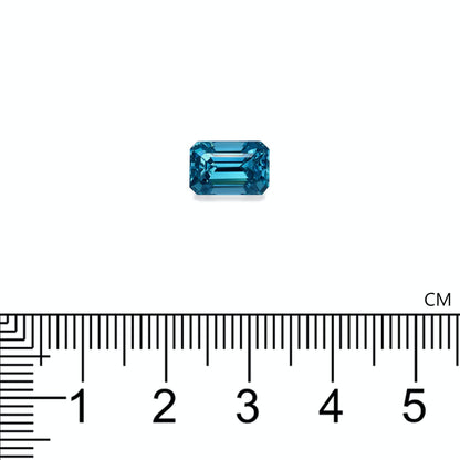 Un Zircon Bleu de 4,29 carats de Bonnot Paris, de taille émeraude et de forme rectangulaire, est présenté à côté d'une règle graduée en centimètres sur un fond blanc uni, mesurant un peu plus de 1 cm.