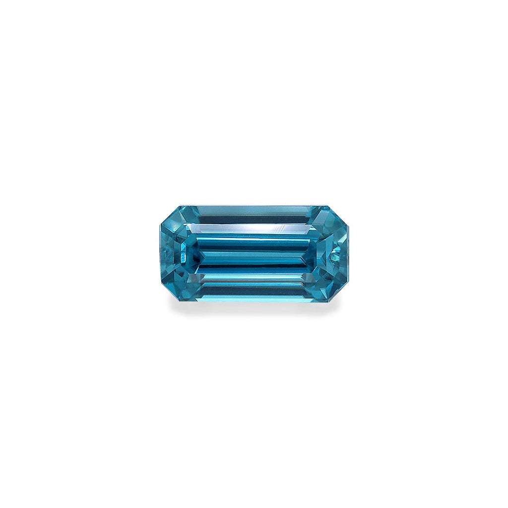 Une pierre précieuse Zircon Bleu rectangulaire allongée facettée de 4,44 ct avec des bords biseautés par Bonnot Paris, reflétant la lumière sur un fond blanc uni.