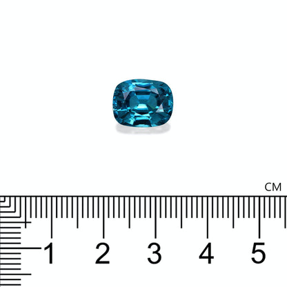 Le Zircon Bleu · 7,58ct de Bonnot Paris, taille coussin, repose sur un fond blanc avec une règle centimétrique en dessous indiquant sa taille à environ 1,2 cm de large.