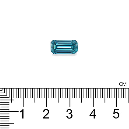 Une petite pierre précieuse rectangulaire Zircon Bleu · 4,75 ct de Bonnot Paris se trouve au-dessus d'une règle marquée en centimètres, mettant en valeur son design en gradins et sa transparence.