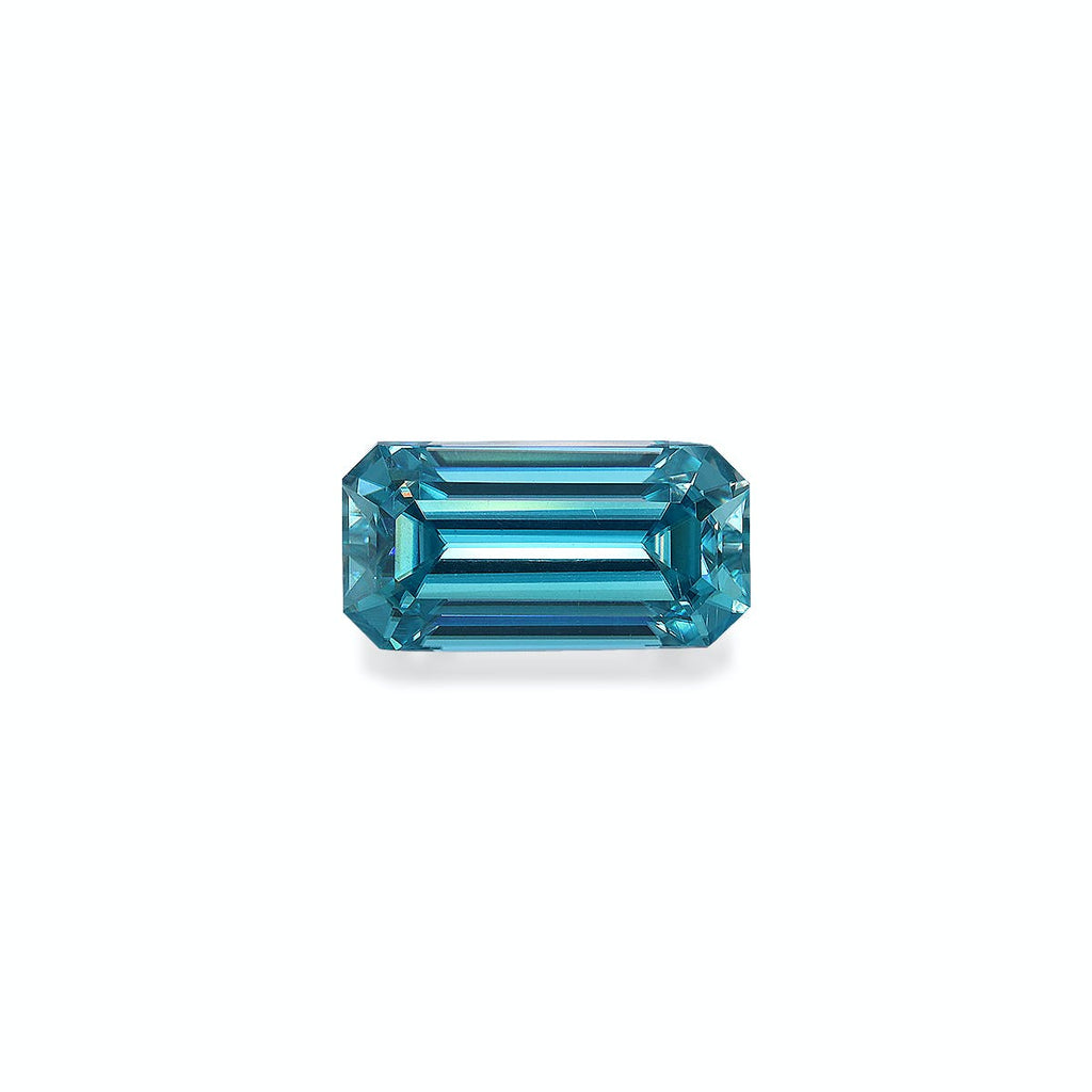 Le Zircon Bleu · 4,75 ct de Bonnot Paris est une pierre précieuse bleue facettée, taille émeraude, de forme rectangulaire allongée et aux coins biseautés, présentée sur un fond blanc uni pour plus de clarté et de brillance réfléchissante.