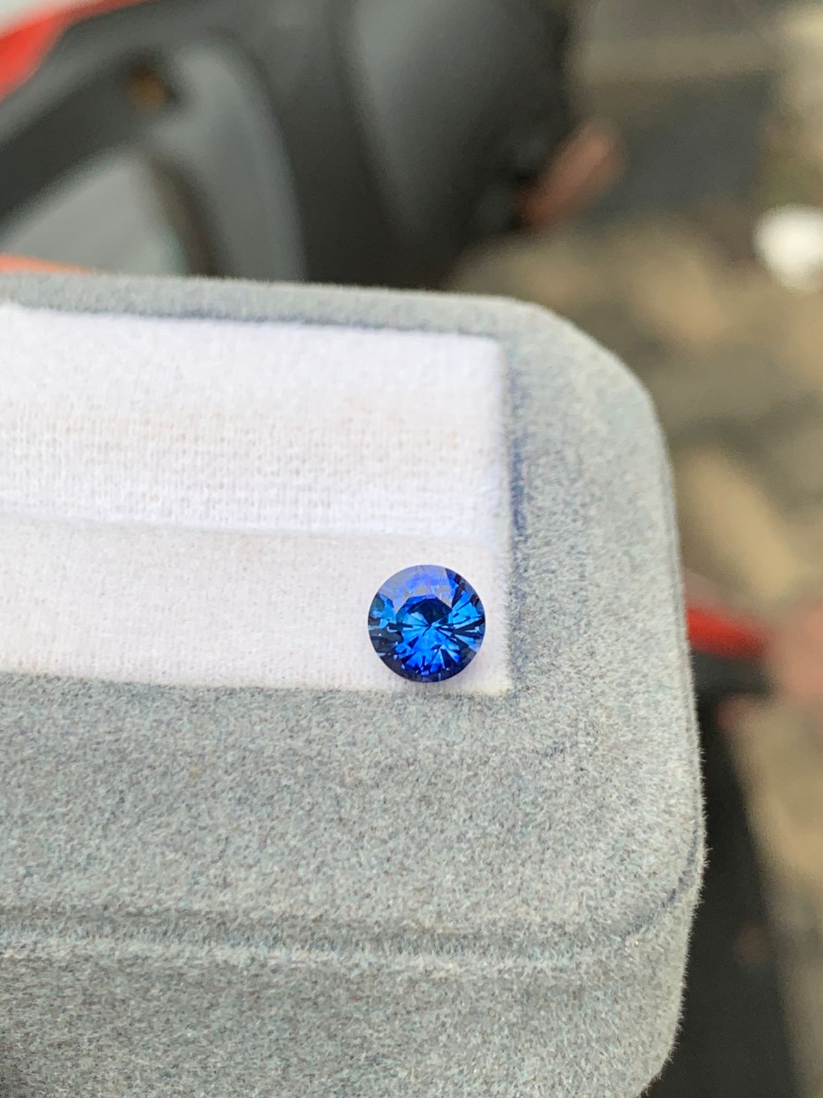 Live 35 Sapphire 1.10 ct deep blue round-cut gemstone from Sri Lanka on gray display pad